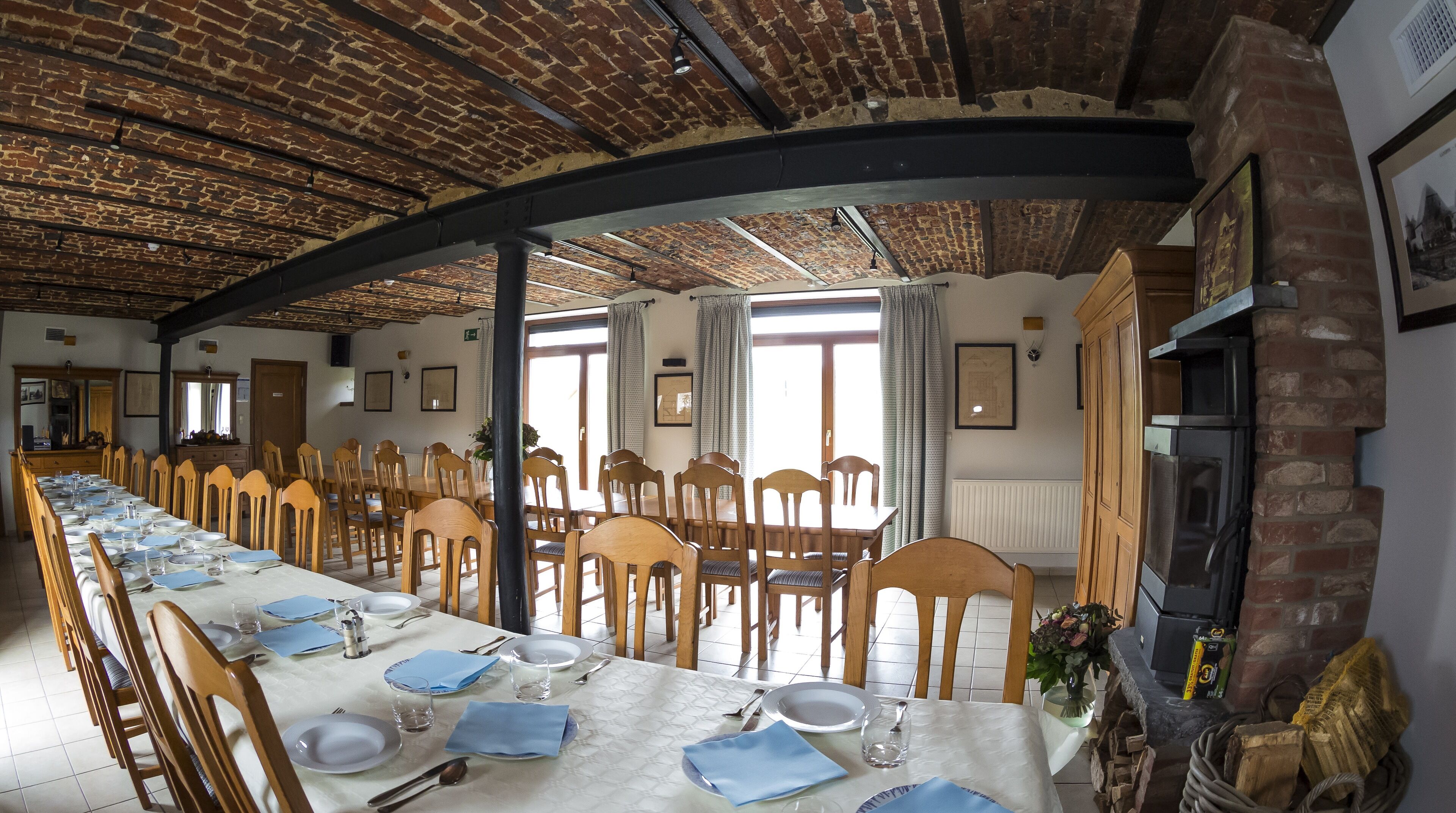 A long dining table set for a meal in a room with brick walls and a high ceiling.