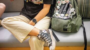 A person sitting on a couch with a backpack containing various badges and patches.