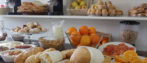 A breakfast buffet with various pastries, fruits, and spreads.