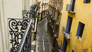 A narrow street with buildings on either side, featuring balconies with wrought iron railings and a mix of architectural styles. - River Hostel (Valencia)