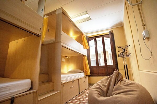 A compact room with bunk beds, a small window, and a radiator. - River Hostel (Valencia)