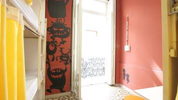 Una habitación con literas, una puerta que da a un balcón y un suelo a cuadros.