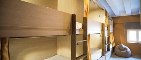 Une chambre avec des lits superposés en bois, un fauteuil poire et une fenêtre.