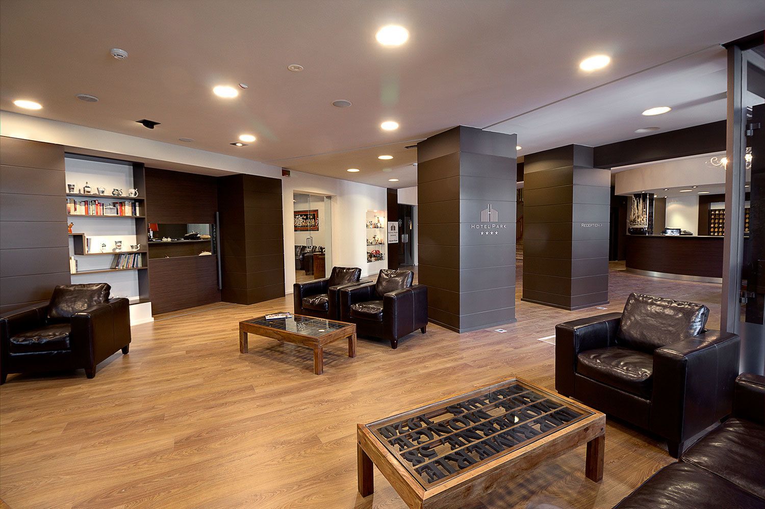 Un hall d’hôtel moderne avec des sièges en cuir, un plancher en bois et un comptoir d’accueil.
