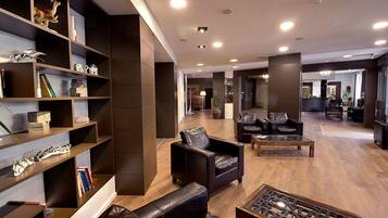 Eine moderne Lobby mit Ledersofas, einem Holztisch und einem Bücherregal mit Dekoration.