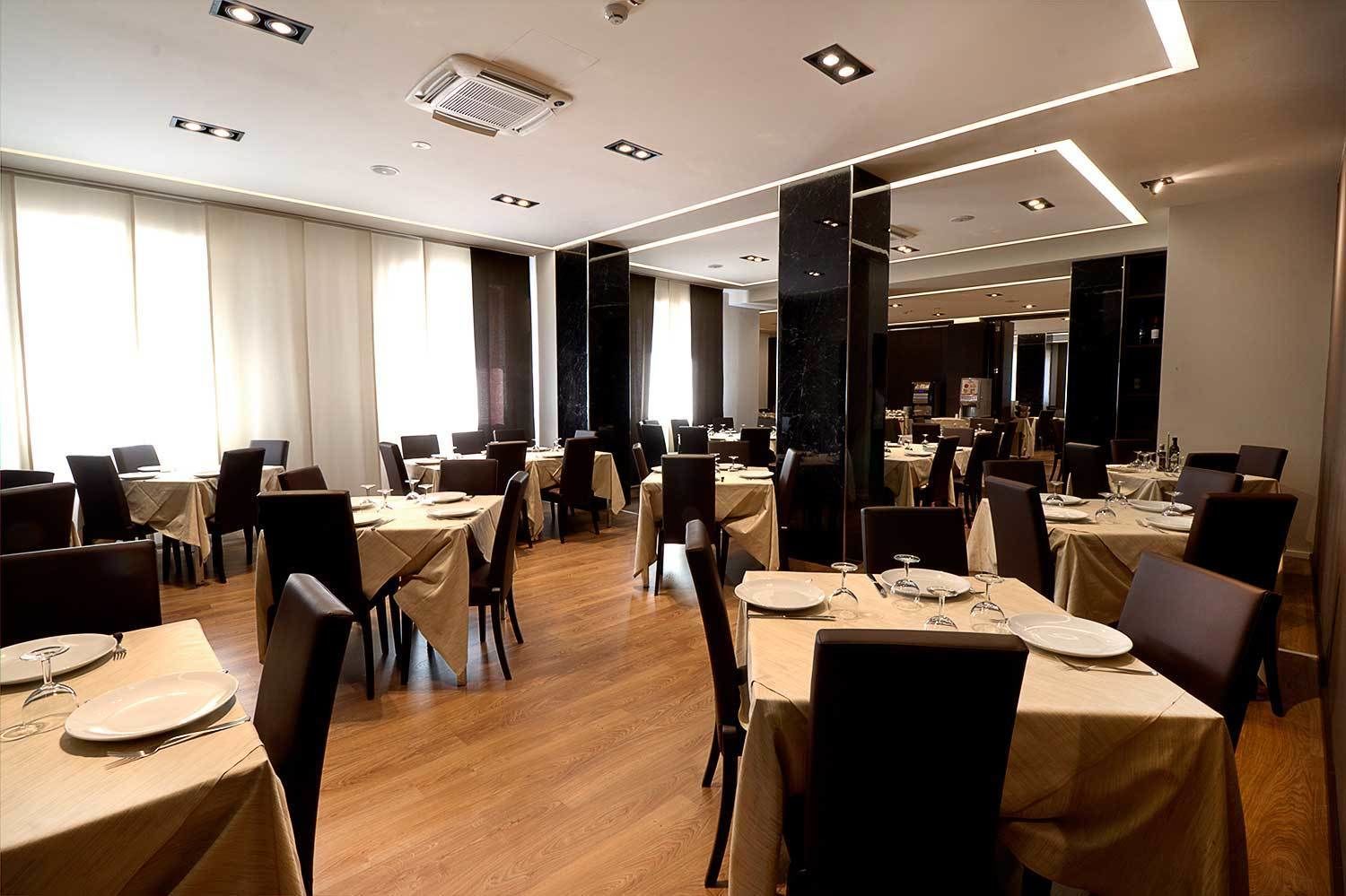 Un amplio comedor con numerosas mesas y sillas, dispuesto en un espacio generoso.