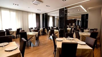 Un amplio comedor con numerosas mesas y sillas, dispuesto en un espacio generoso.