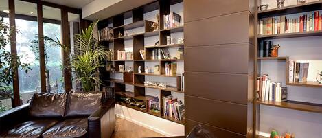 A modern library with leather sofas, bookshelves, and a large window.