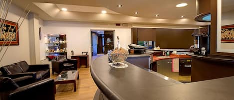 A modern living room with a curved black countertop, a coffee machine, and a dining area with a red countertop.