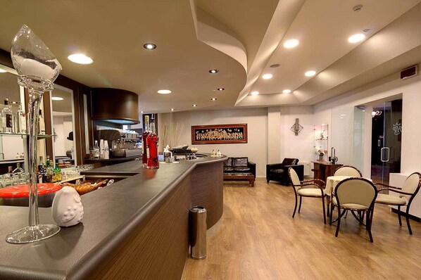 A modern bar area with a counter, bar stools, and a seating area with chairs. - Hotel Park (Castiglion Fiorentino)