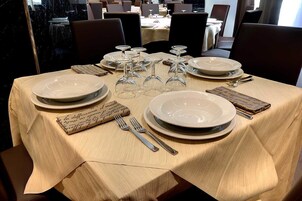 Una mesa de comedor dispuesta con platos, vasos y cubiertos, con un menú sobre la mesa.
