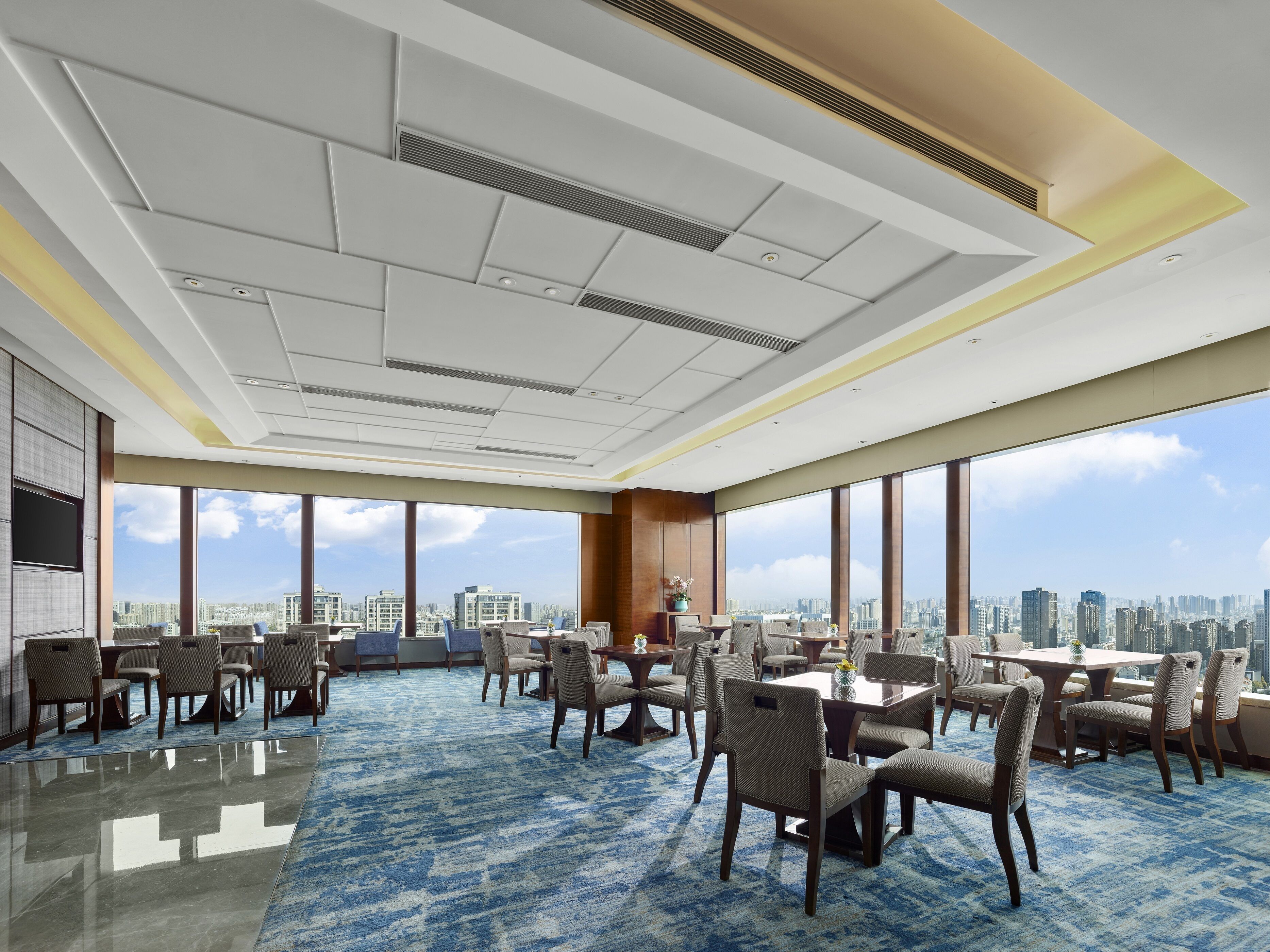 A spacious conference room with large windows offering a city view, a polished floor, and modern furniture.
