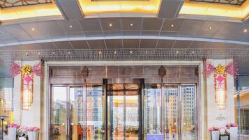 L’entrée d’un hôtel au design moderne, avec une porte d’entrée en verre, un éclairage décoratif et une vue sur le paysage urbain à travers les fenêtres.