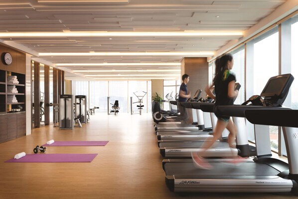A gym with treadmills, yoga mats, and exercise equipment.
