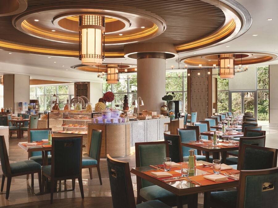 Un restaurant spacieux avec de hauts plafonds, un éclairage moderne et un îlot central où sont présentés divers plats.