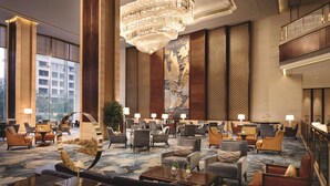 A spacious lobby with multiple seating areas, a large chandelier, and a large window providing a view of the city. - Shangri-La Hefei (Hefei)