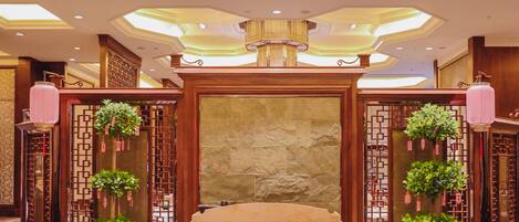 Un área de recepción con pared de piedra, paneles de madera y plantas en macetas.