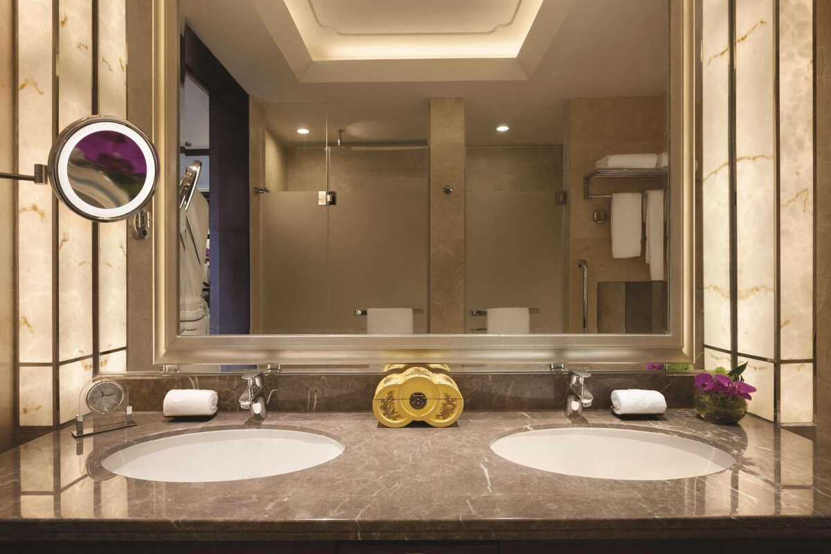 A bathroom with two sinks, a large mirror, and a shower.