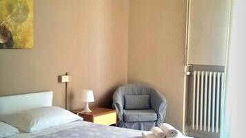A bedroom with a bed, a chair, a radiator, and a ceiling light.