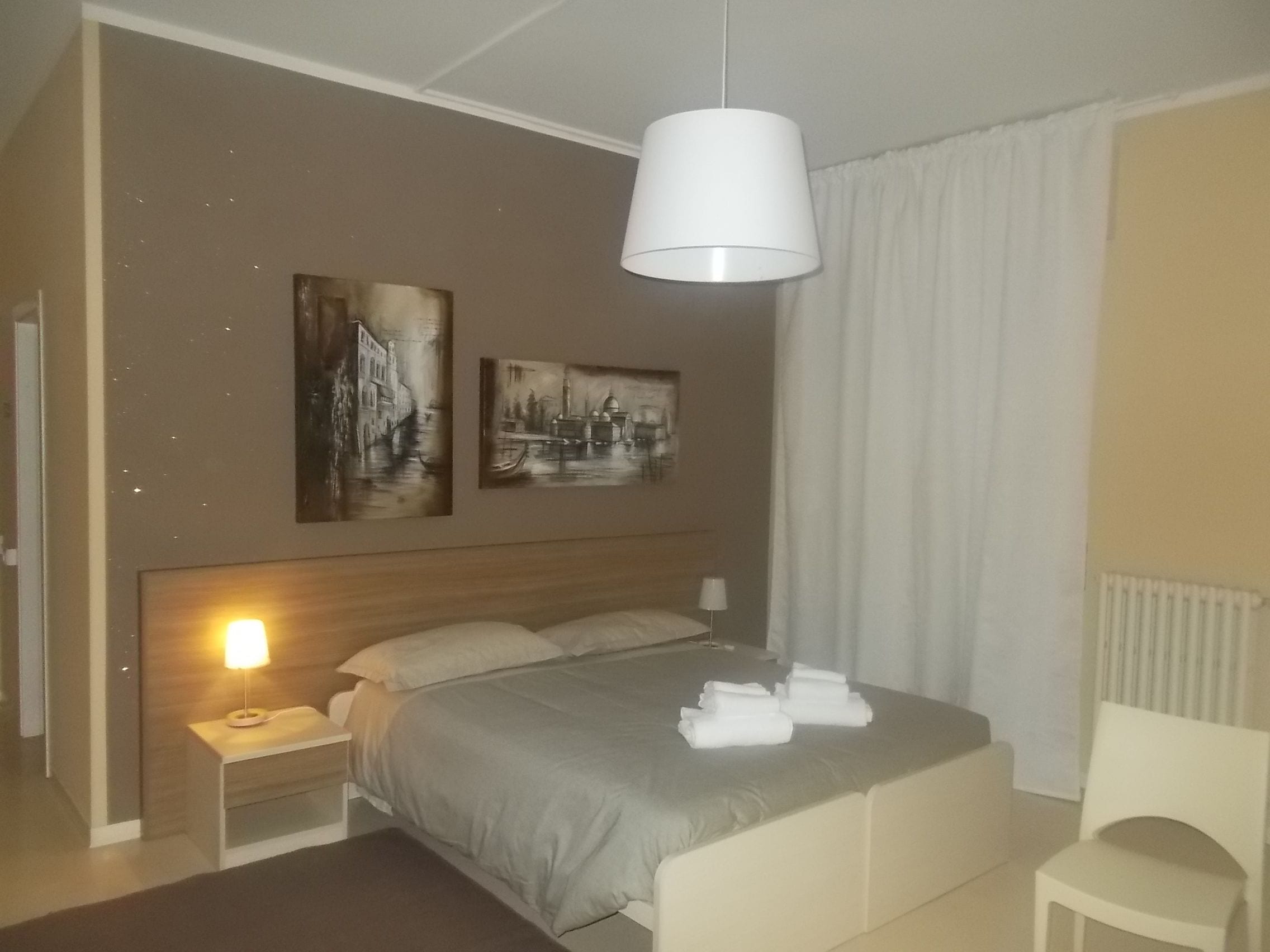 A hotel room with a bed, bedside tables, a lamp, and artwork on the wall.