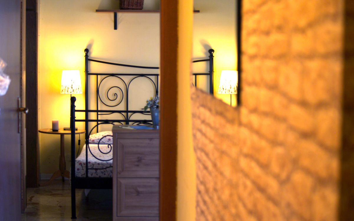 A bedroom with a metal bed frame, a bedside table with a lamp, and a dresser.