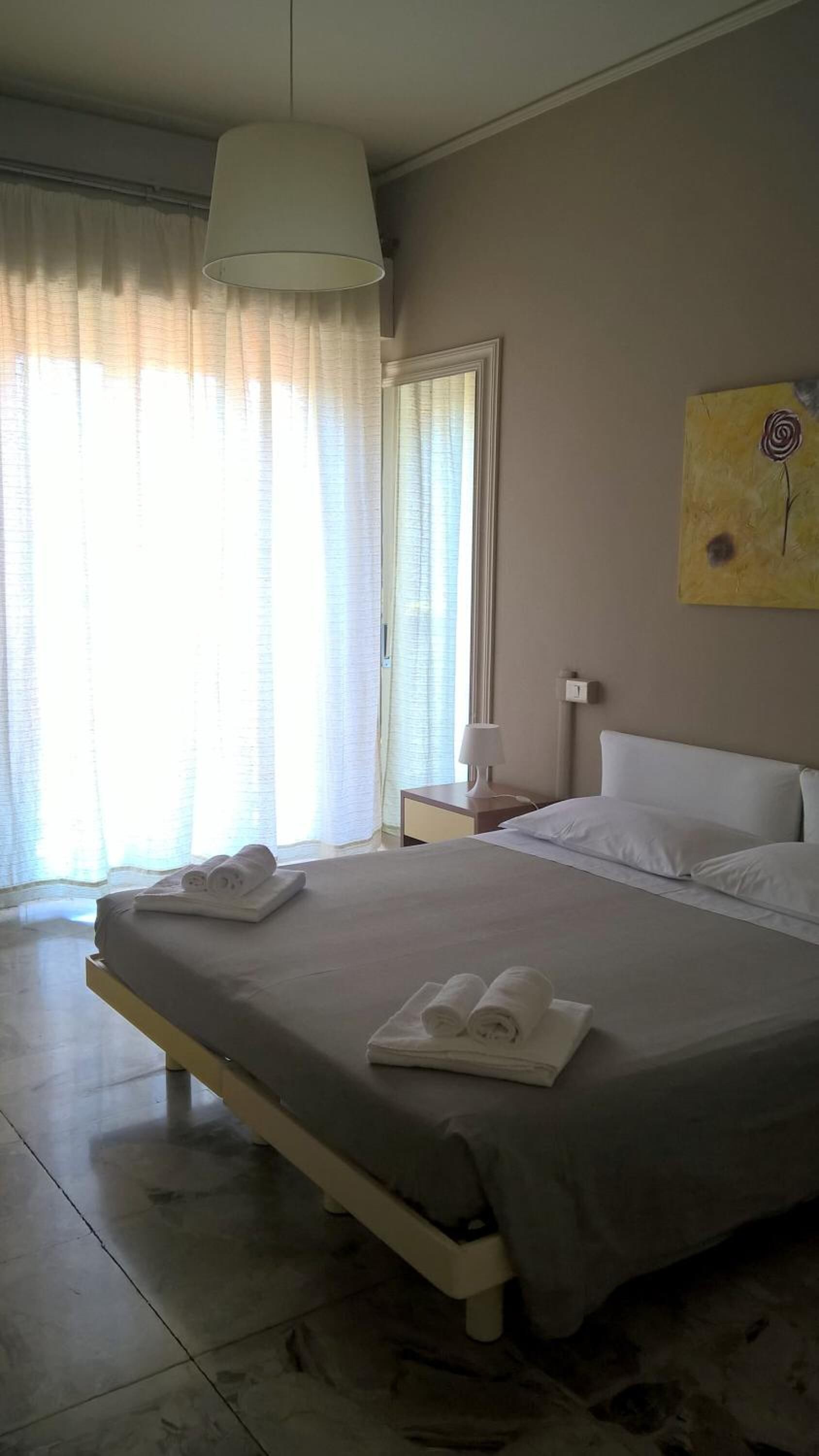Una habitación de hotel con una cama, una mesita de noche, una lámpara y un cuadro en la pared.