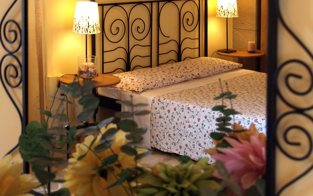 A bedroom with a bed, two bedside lamps, a bedside table, and a nightstand.