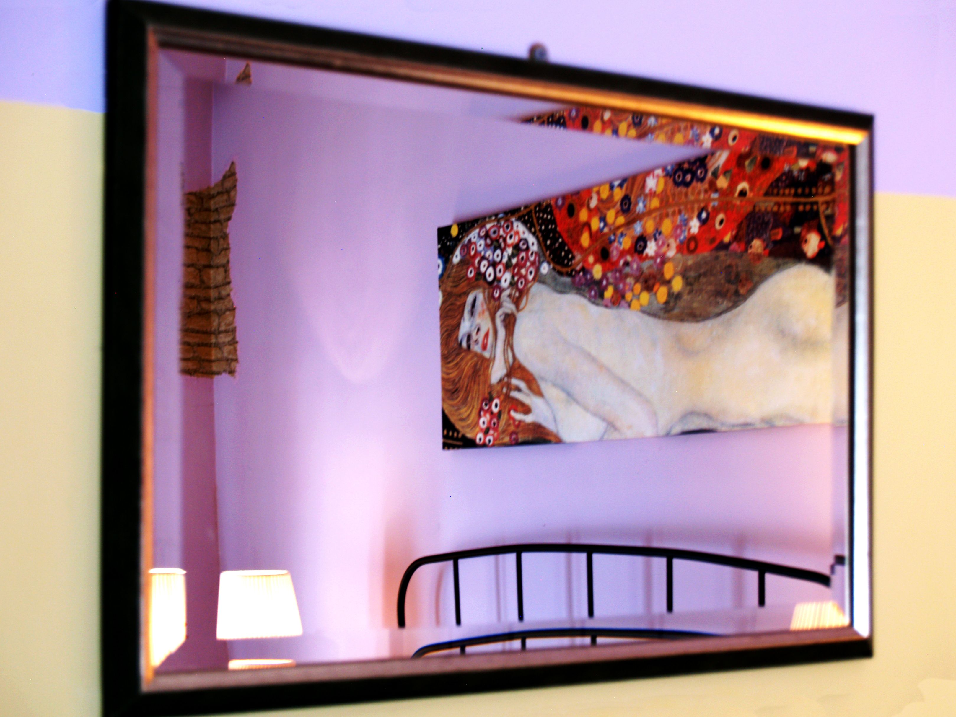 Ein gerahmtes Kunstwerk an einer Wand über einem Bett mit Metallgestell.