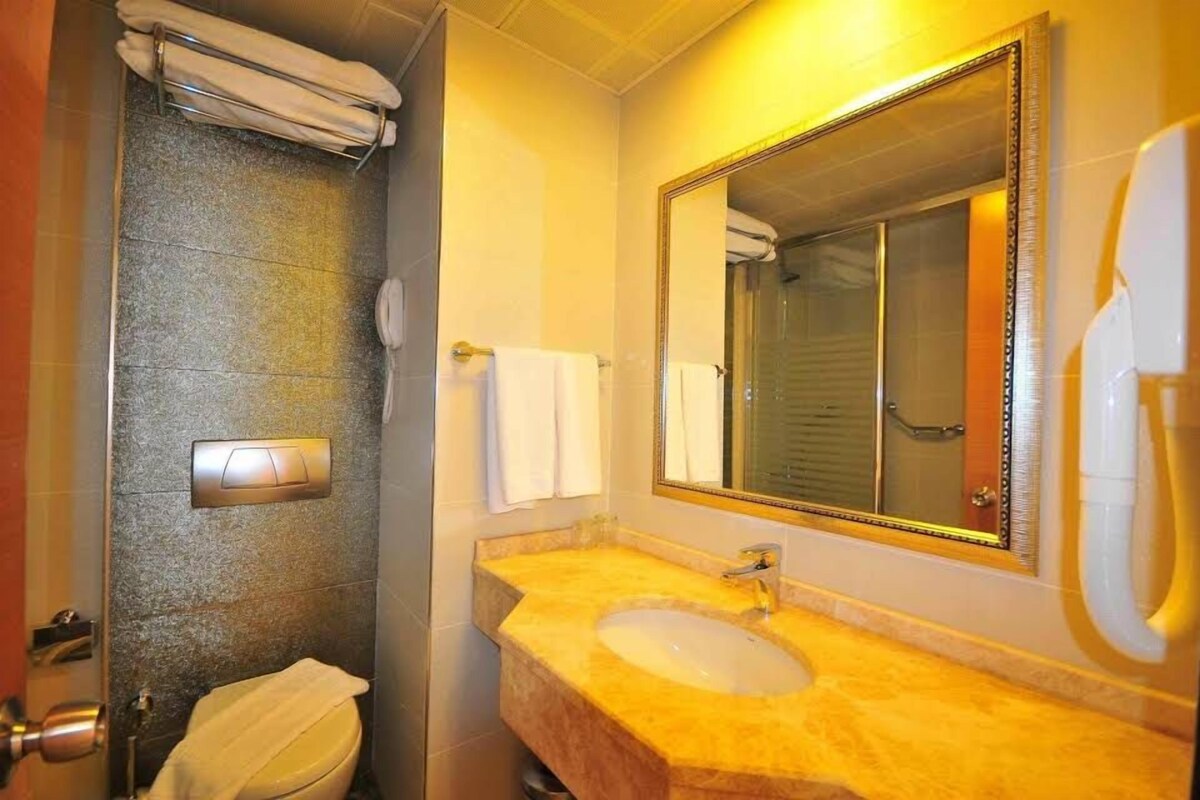 A bathroom with a marble sink, a large mirror, and a towel rack.