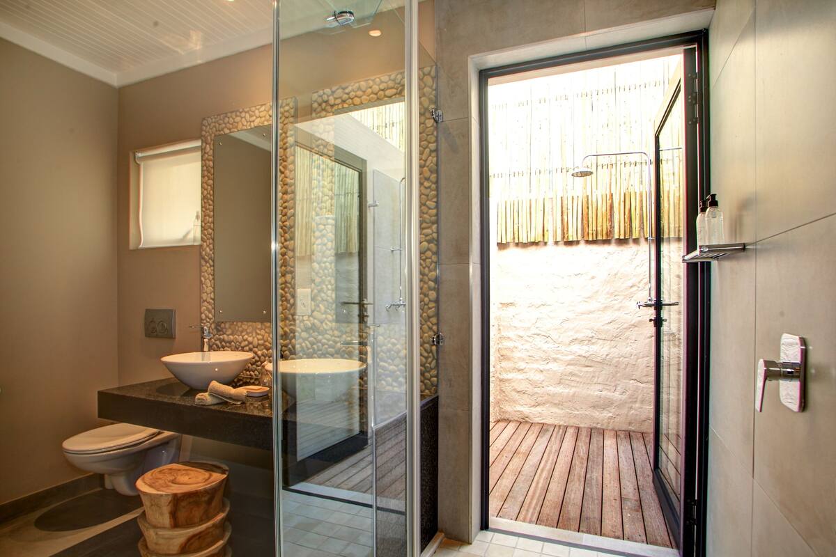 A modern bathroom with a glass-enclosed shower, a large sink, and a toilet.
