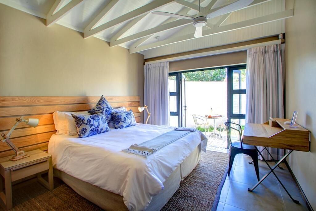 Un dormitorio con una cama grande, un escritorio y una silla. Hay una ventana con cortinas y vistas al exterior.