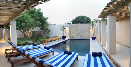 Una piscina al aire libre, sillones reclinables de piscina