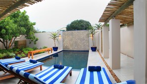 Una piscina al aire libre, sillones reclinables de piscina