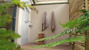 A bathroom with a wooden floor, a sink, and two towels hanging on the wall. - Scallop Guest Lodge (Plettenberg Bay)