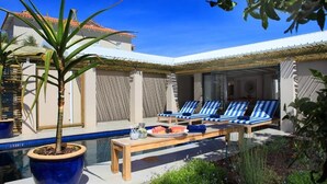 A poolside area with lounge chairs, a table with fruit, and a potted plant. - Scallop Guest Lodge (Plettenberg Bay)