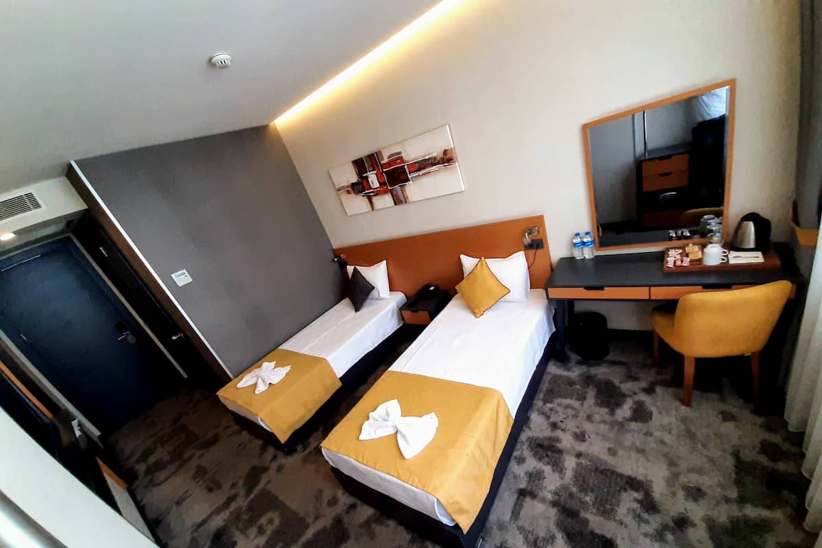 A hotel room with two beds, a desk, a chair, a mirror, and a wardrobe.