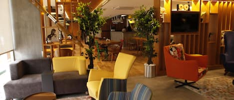 Un intérieur moderne comprenant un canapé, des fauteuils, un coin repas et un téléviseur.