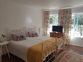 A bedroom with a bed, a bedside table, a TV, and curtains.