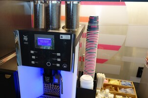 Una cafetera con pantalla digital y zona para colocar tazas.
