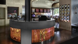 A reception area with a curved counter, a modern chandelier, and a wall with circular mirrors.