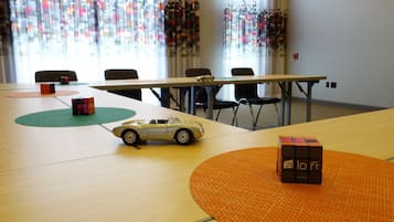 Ein Konferenzraum mit einem langen Tisch, Stühlen, einem Zauberwürfel, einem Spielzeugauto und einer Puzzlespielmatte.