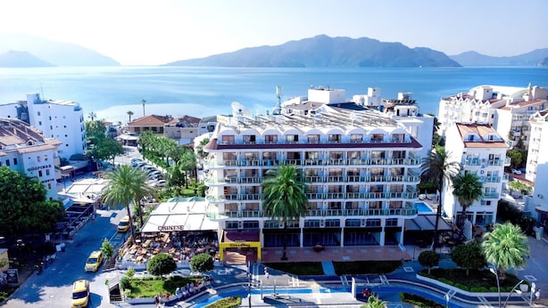 Un hotel de varios pisos con balcones, una zona de piscina y vistas al mar.