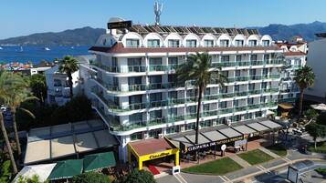 Un hotel de varios pisos con balcones, una terraza en la azotea y vista al mar.