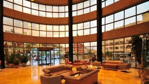 A spacious lobby with a curved glass ceiling, multiple seating areas, and a central entrance. - Golden Rock Beach Hotel - All Inclusive (Marmaris)