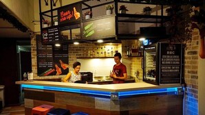 Zona de bar con una pizarra de menú, taburetes y una barra.