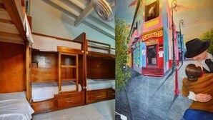 Una habitación con literas, un mural de una calle colorida y un ventilador en el techo.