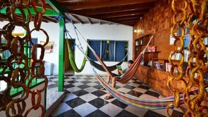 Una habitación con una hamaca, piso a cuadros, paredes de madera y una estantería.
