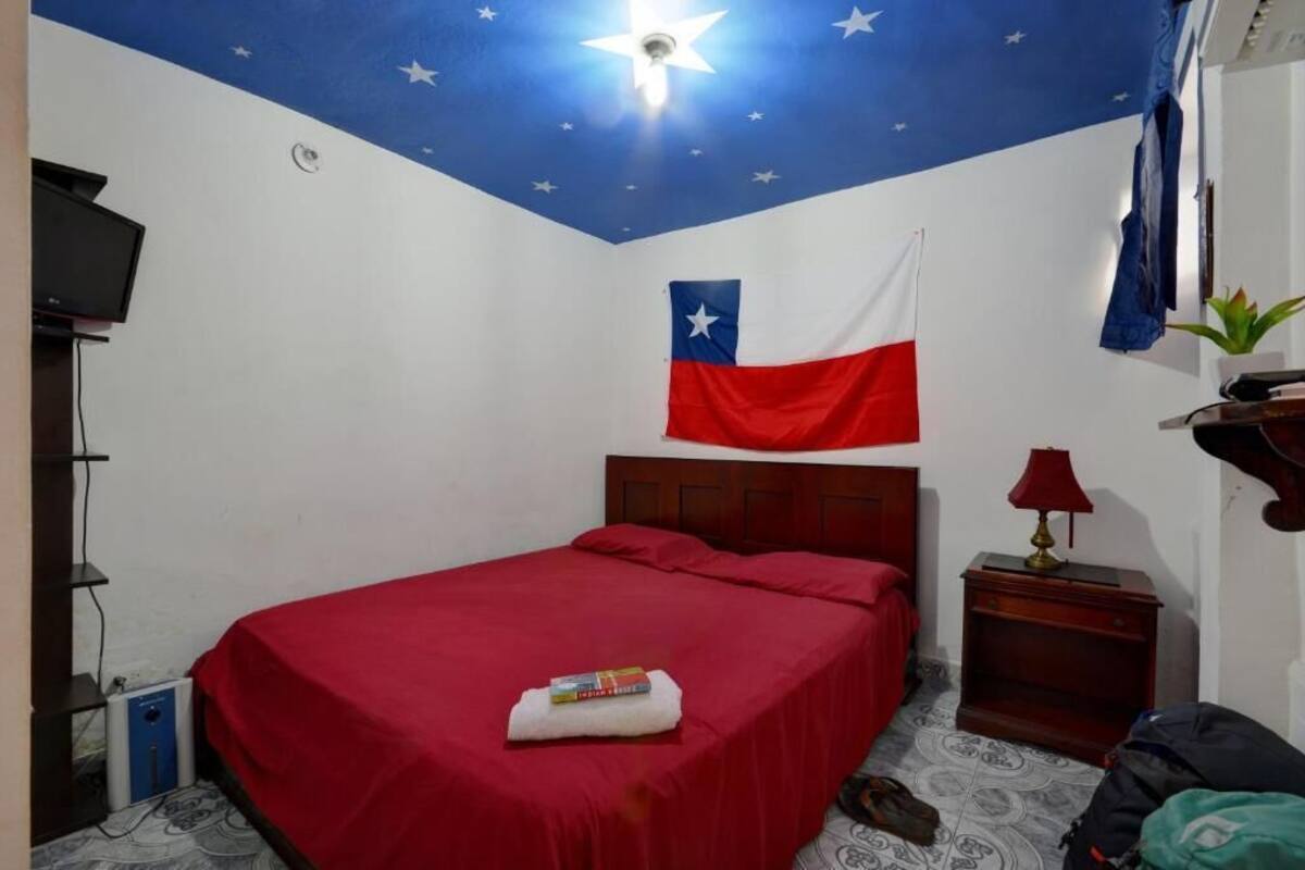 Un dormitorio con cama, mesita de noche, una bandera y decoración de estrellas en el techo.