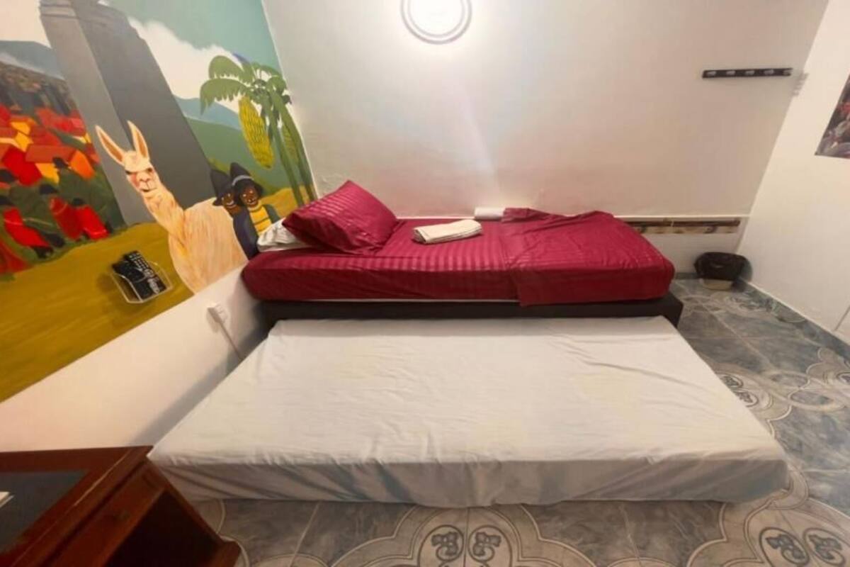 Una habitación con una cama, un mural y una pequeña mesa.