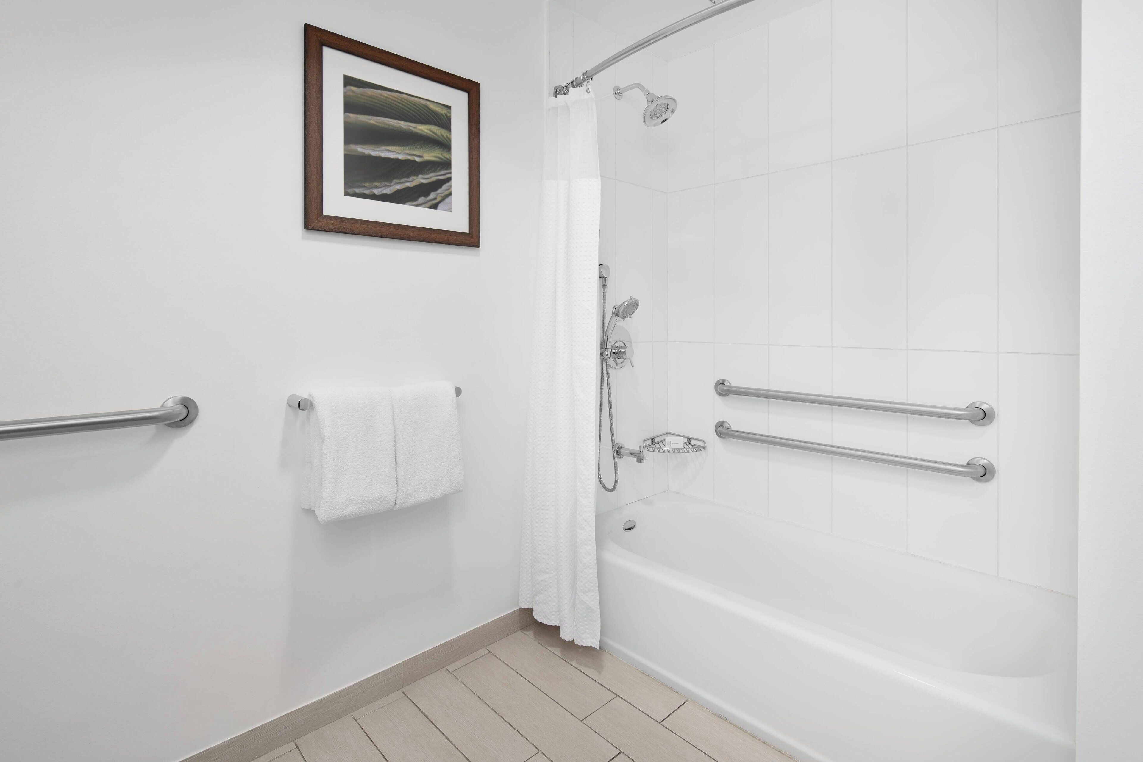 Un baño moderno con bañera, ducha y barras de apoyo.